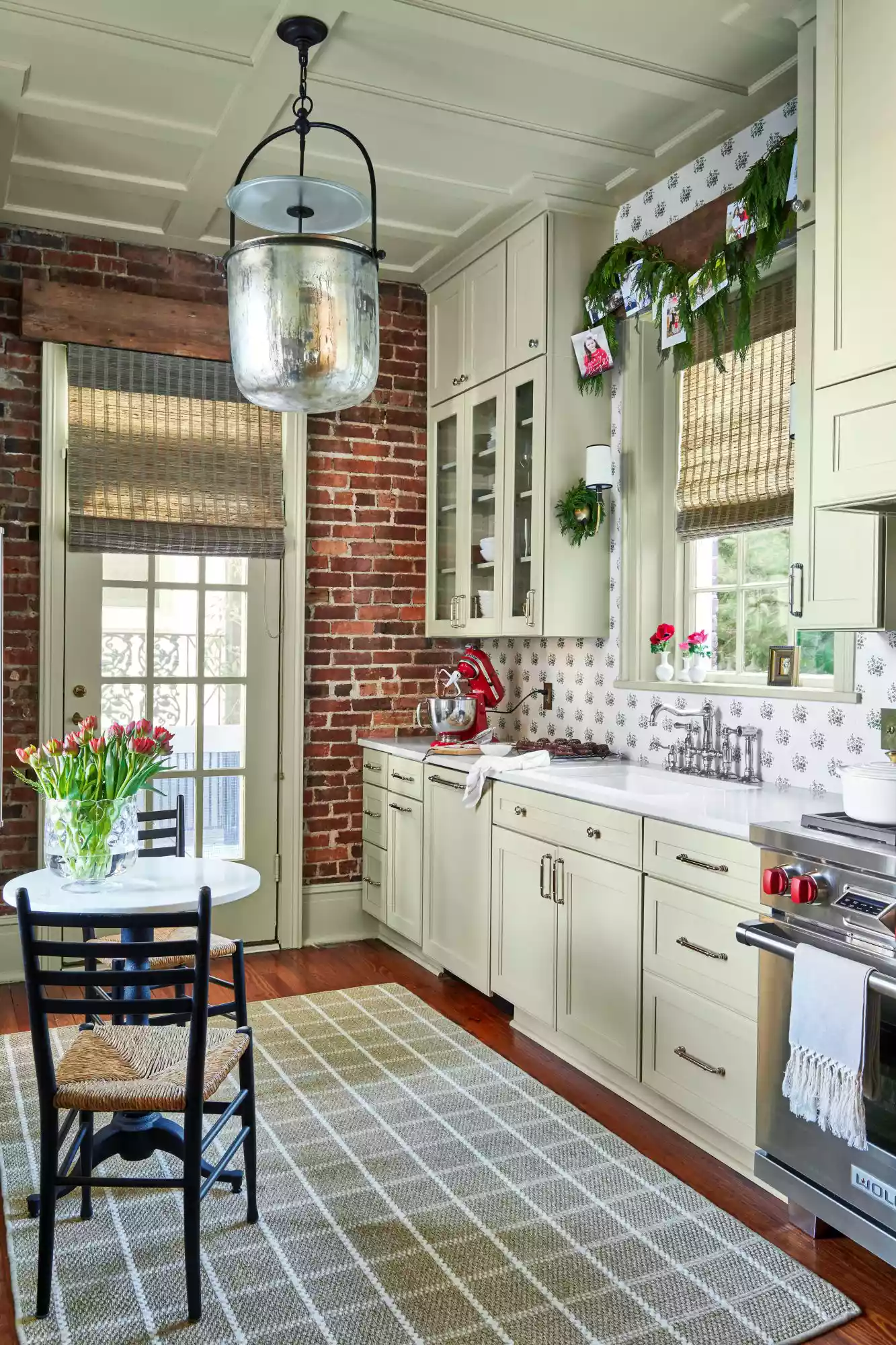 Galley kitchen with light green cabinetry and exposed brick wall