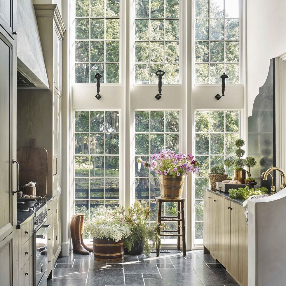 a wall of windows brings in natural light to a galley kitchen with stone countertops and floors