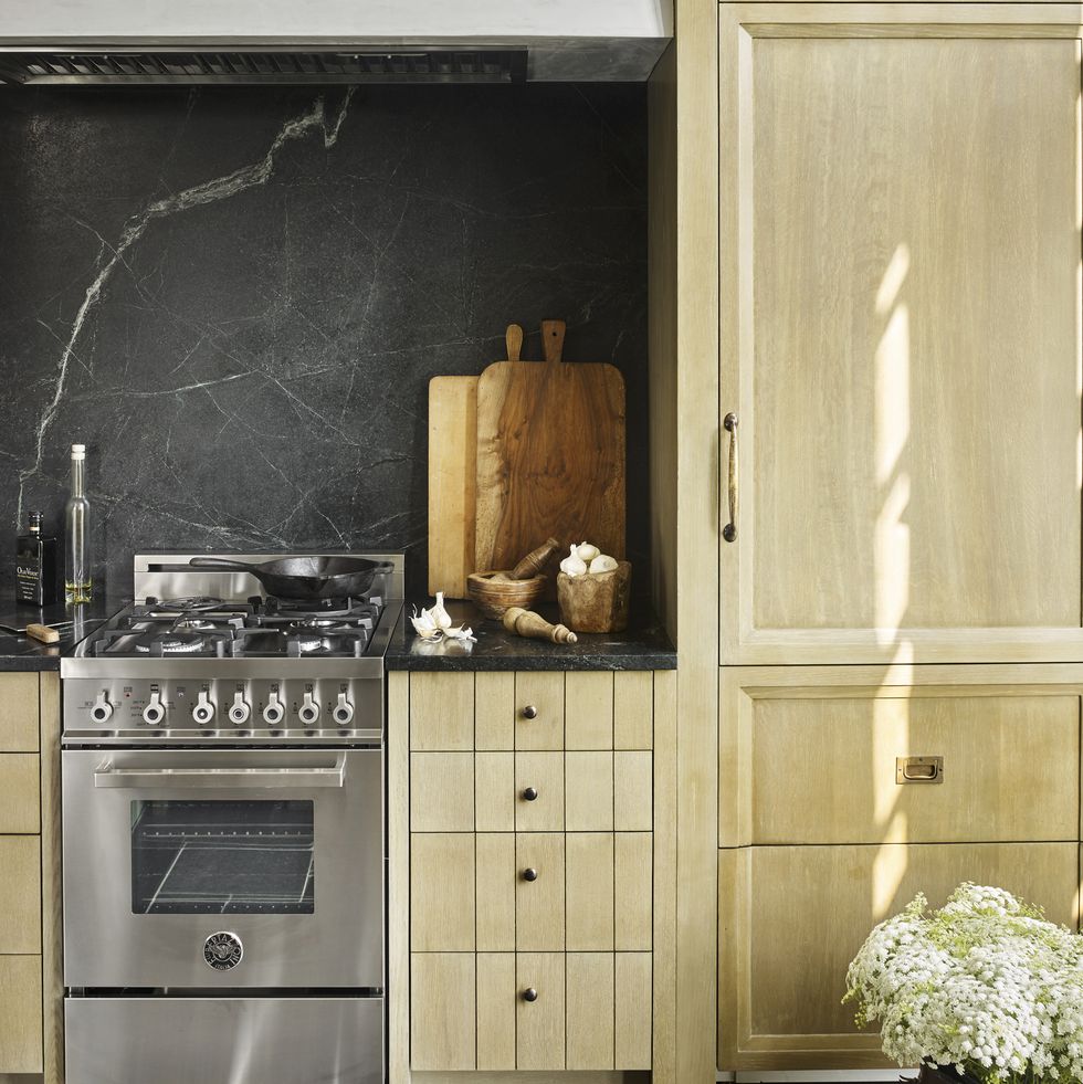 a galley kitchen with warm wood grain cabinets and a stainless steel range