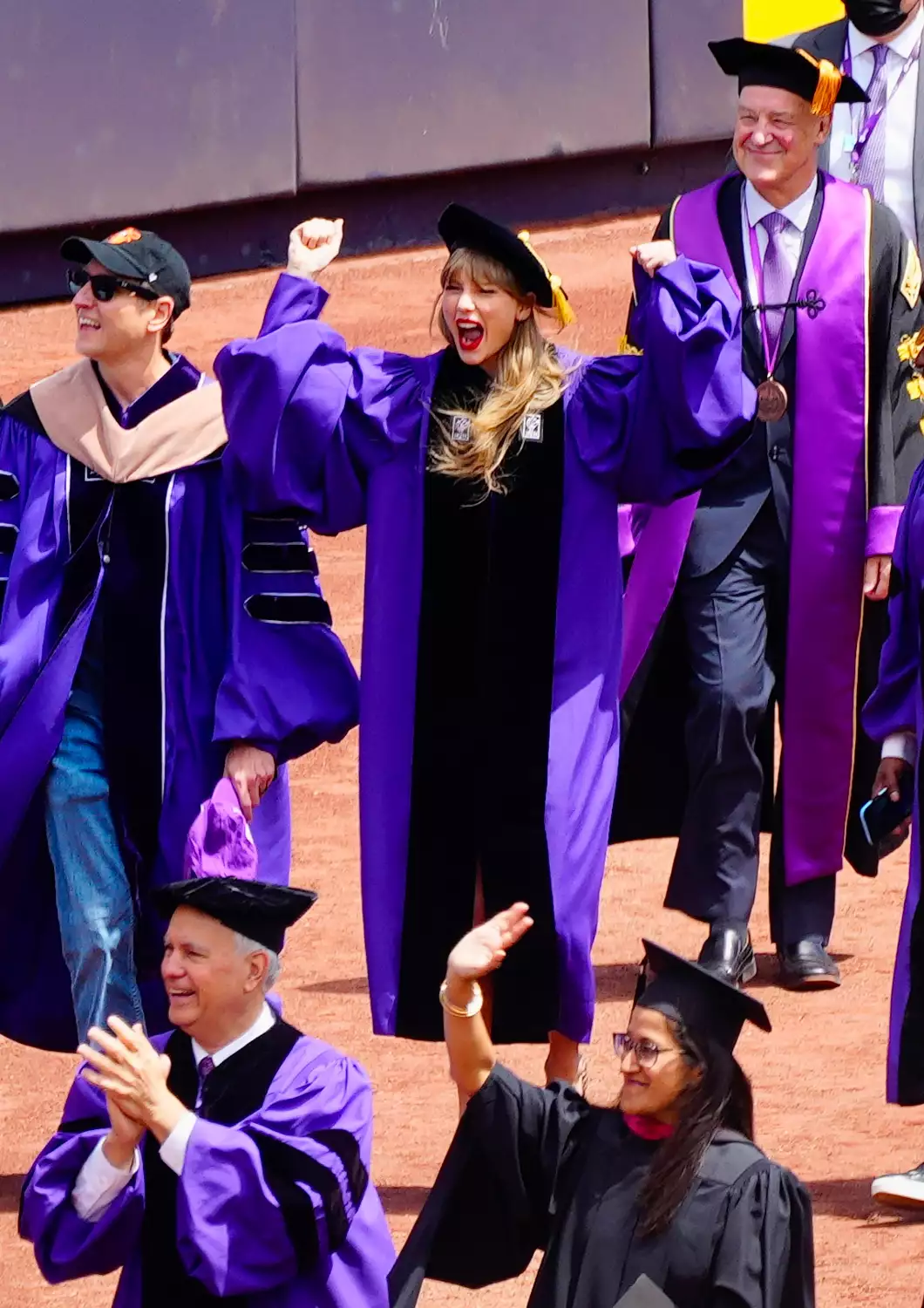 Taylor Swift receives an honorary degree from NYU at Yankee Stadium in New York City. The 32 year old pop star pumped her fists in the air while wearing a cap and gown.