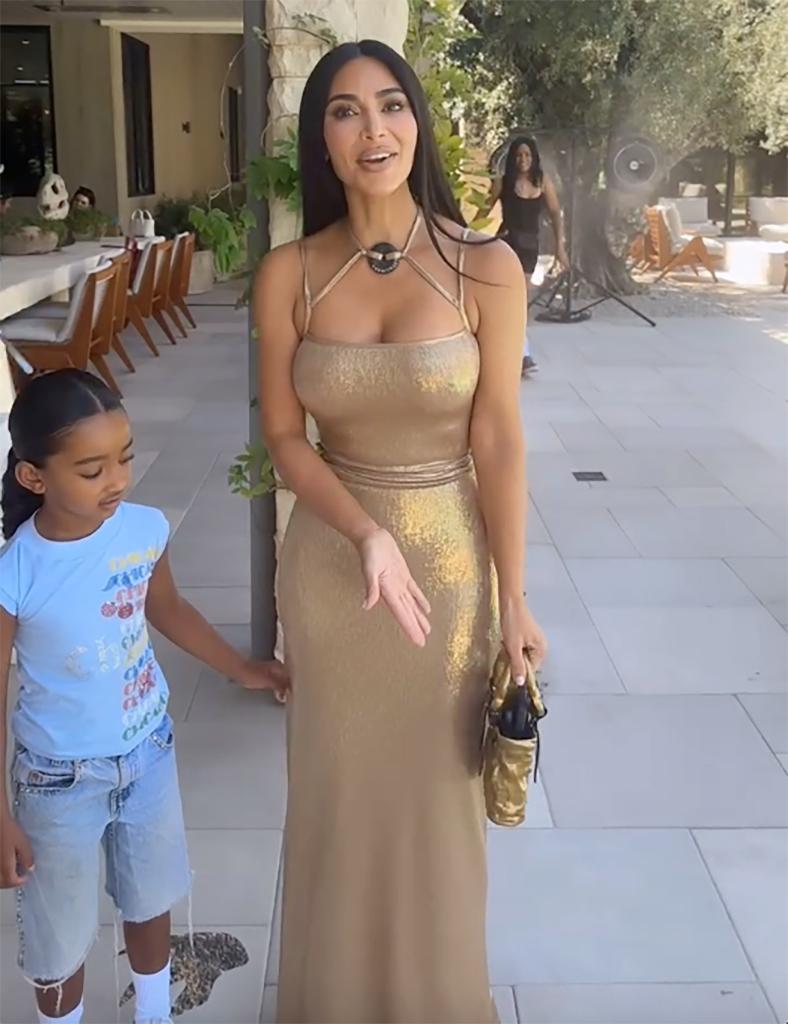 kim kardashian in a gold gown standing with her daughter chicago